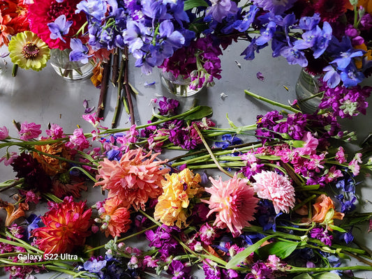 workbench with bright colored cut flower stems  laying on the workbench. 